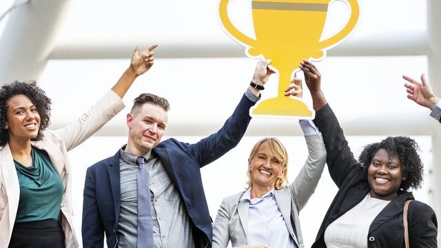 professionals holding a trophy symbolising a reward system